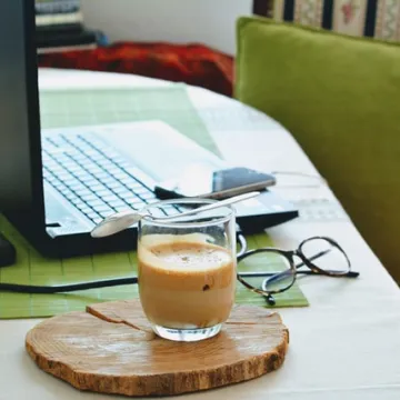 Laptop auf Tisch, daneben Tasse und Brille