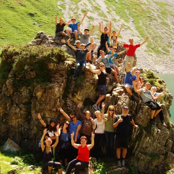 Fotocredit: ÖDV Das Bild zeigt eine Gruppe junger Menschen vor und auf einem großen Stein.